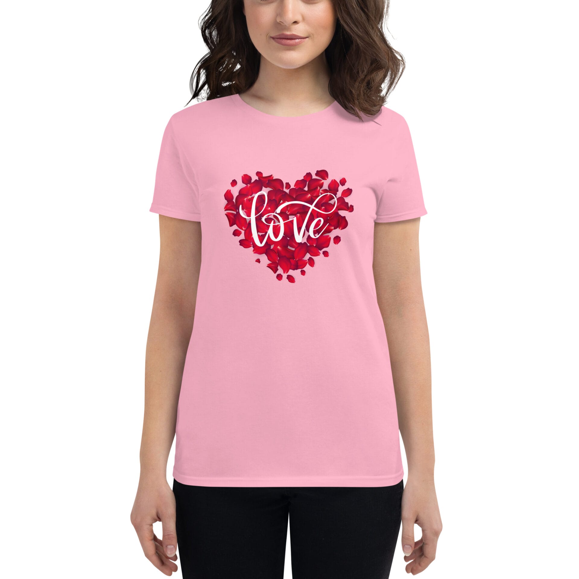 A person wears a pink t-shirt featuring a heart made of red rose petals with the word love elegantly scripted in white standing against a neutral background.