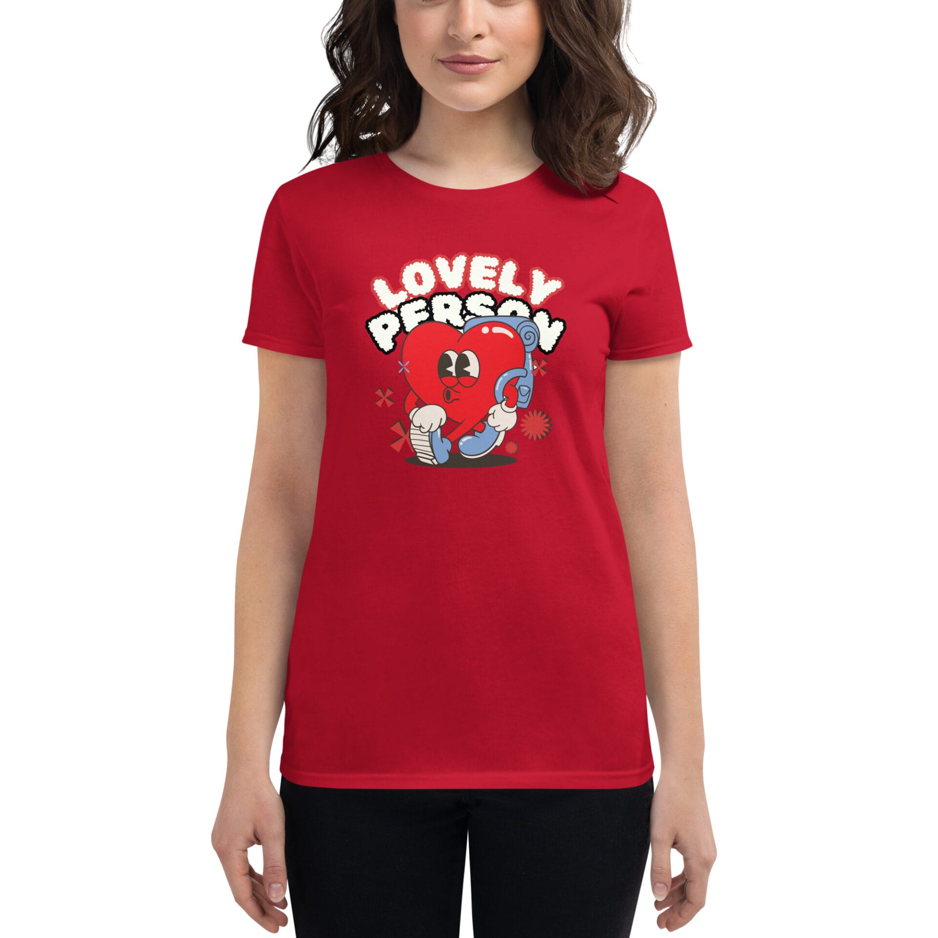A person wears a red t-shirt featuring a cartoon heart holding a telephone with the text "LOVELY PERSON" above it in a playful font. The background is plain.