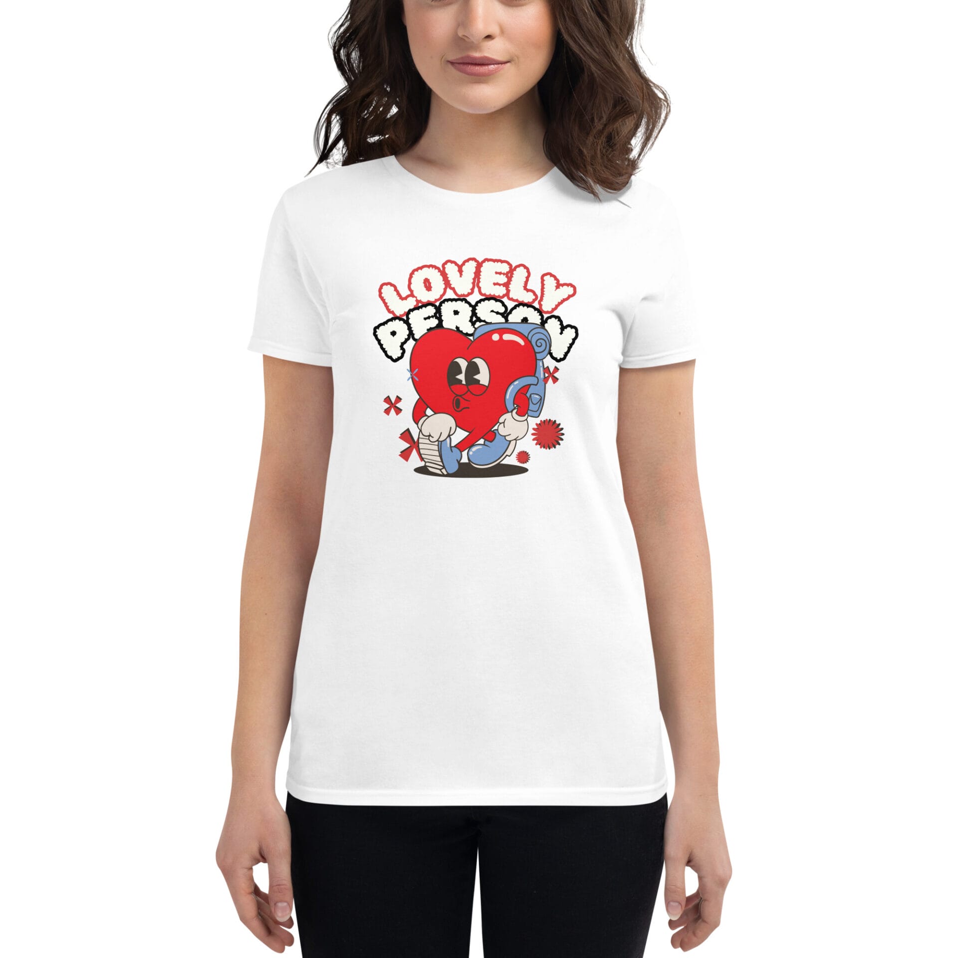 A woman wears a white t-shirt featuring a cartoonish red heart character with eyes and boxing gloves alongside the text "LOVELY PERSON" in bold playful letters.