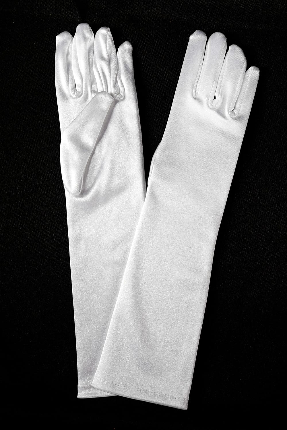 Two long white satin gloves are displayed side by side with their fingers slightly spread on a black background creating a contrast that highlights their smooth texture and shine.
