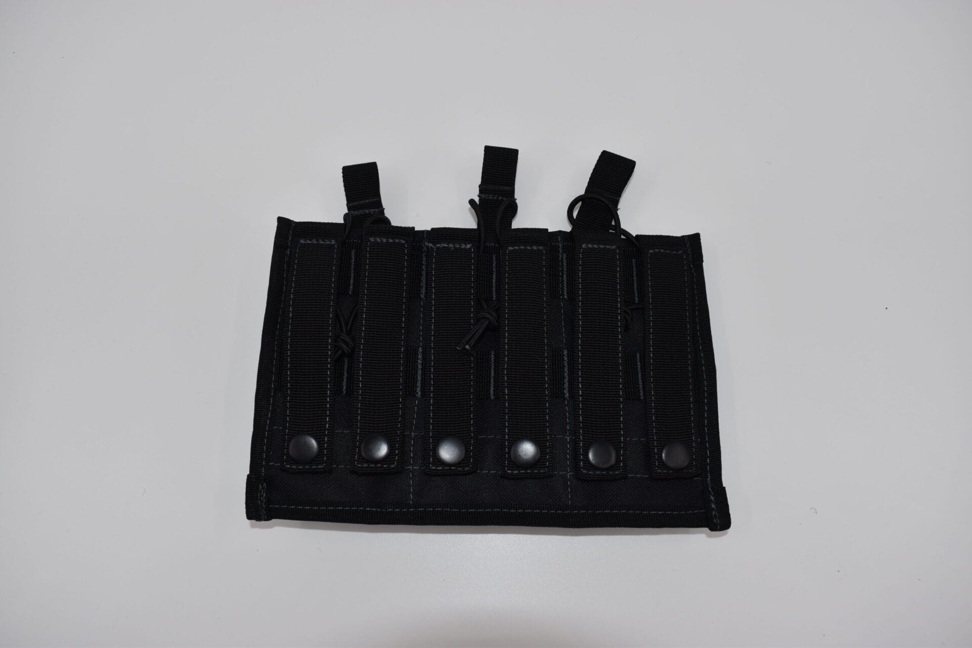 A black tactical gear panel features multiple vertical slots for holding items secured by snaps and strings on a plain light background  indicating a functional design for carrying equipment.