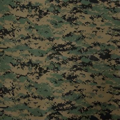 A camouflage fabric displays a pattern with varying shades of green and brown interspersed with black blotches creating a textured appearance suitable for military or outdoor use.