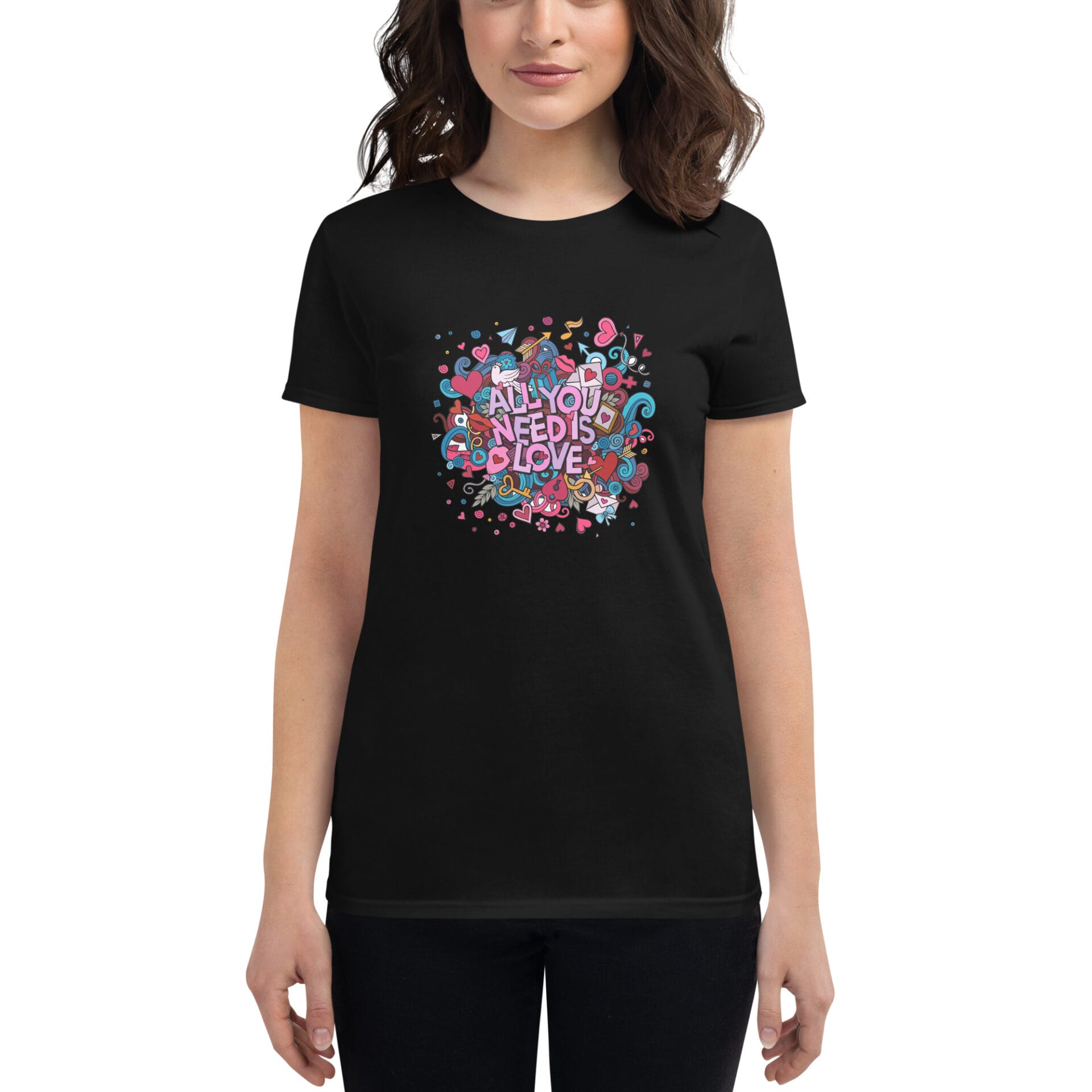 A woman wears a black t-shirt featuring colorful  whimsical art with the text All You Need Is Love surrounded by hearts and playful designs in a bright  cheerful composition.