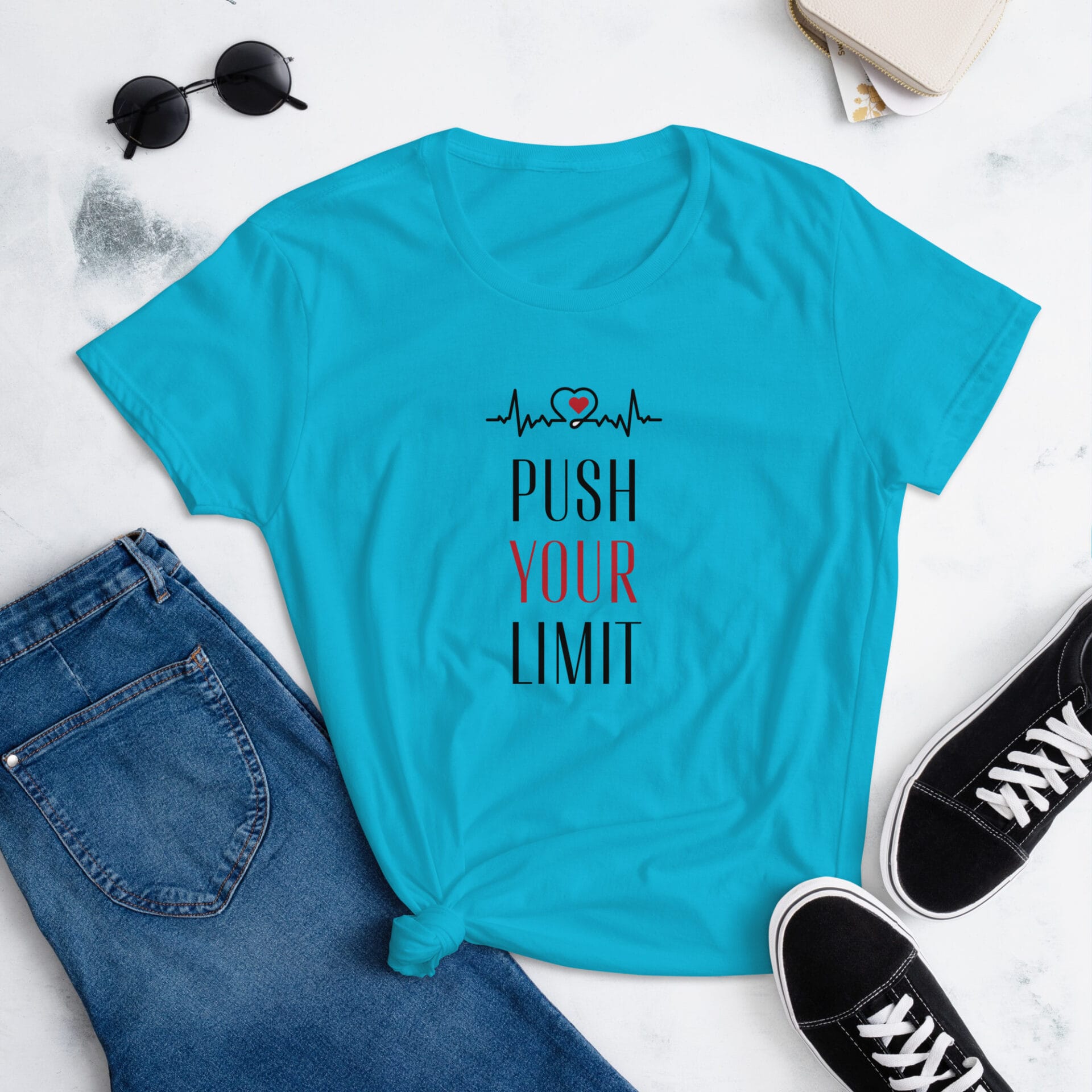 A turquoise t-shirt with the text "PUSH YOUR LIMIT" and a heart rate graphic is displayed with jeans and black sneakers on a light background  suggesting a casual  motivational outfit.