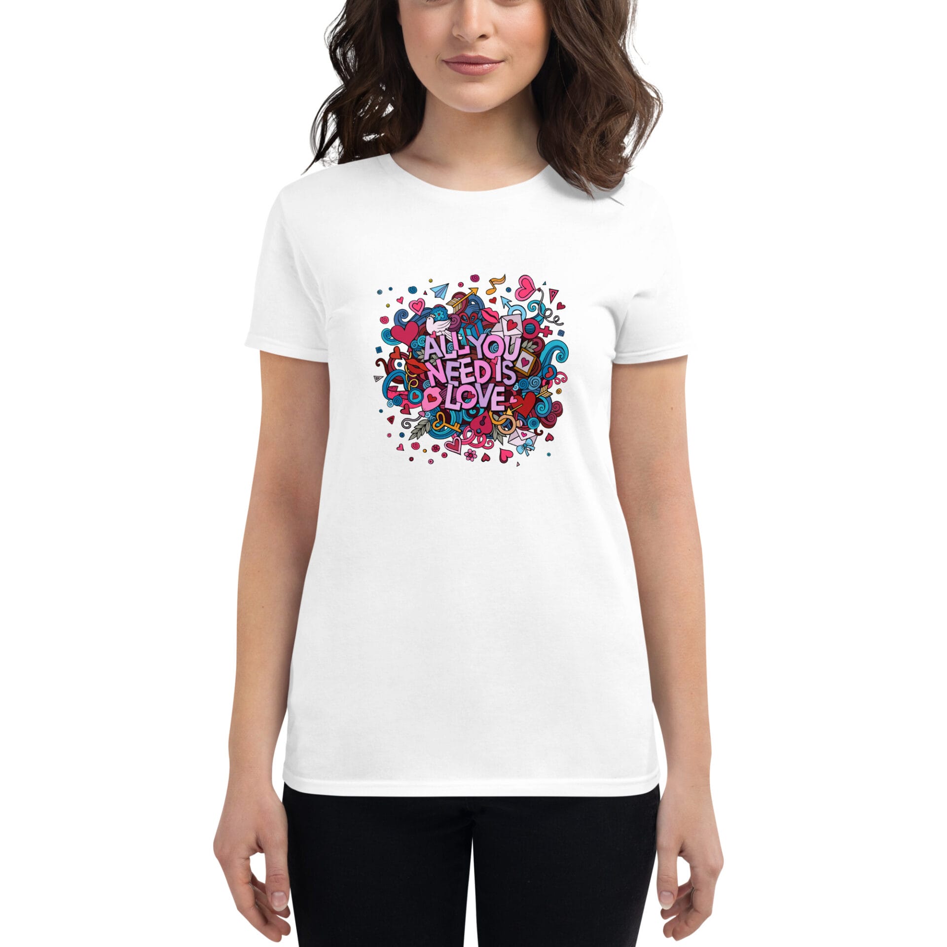 A woman is wearing a white t-shirt featuring colorful graphic text that reads "ALL YOU NEED IS LOVE" surrounded by vibrant designs and patterns against a plain background.